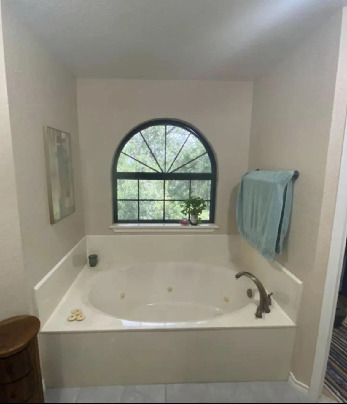 Bathtub beneath an arched window before conversion to a shower