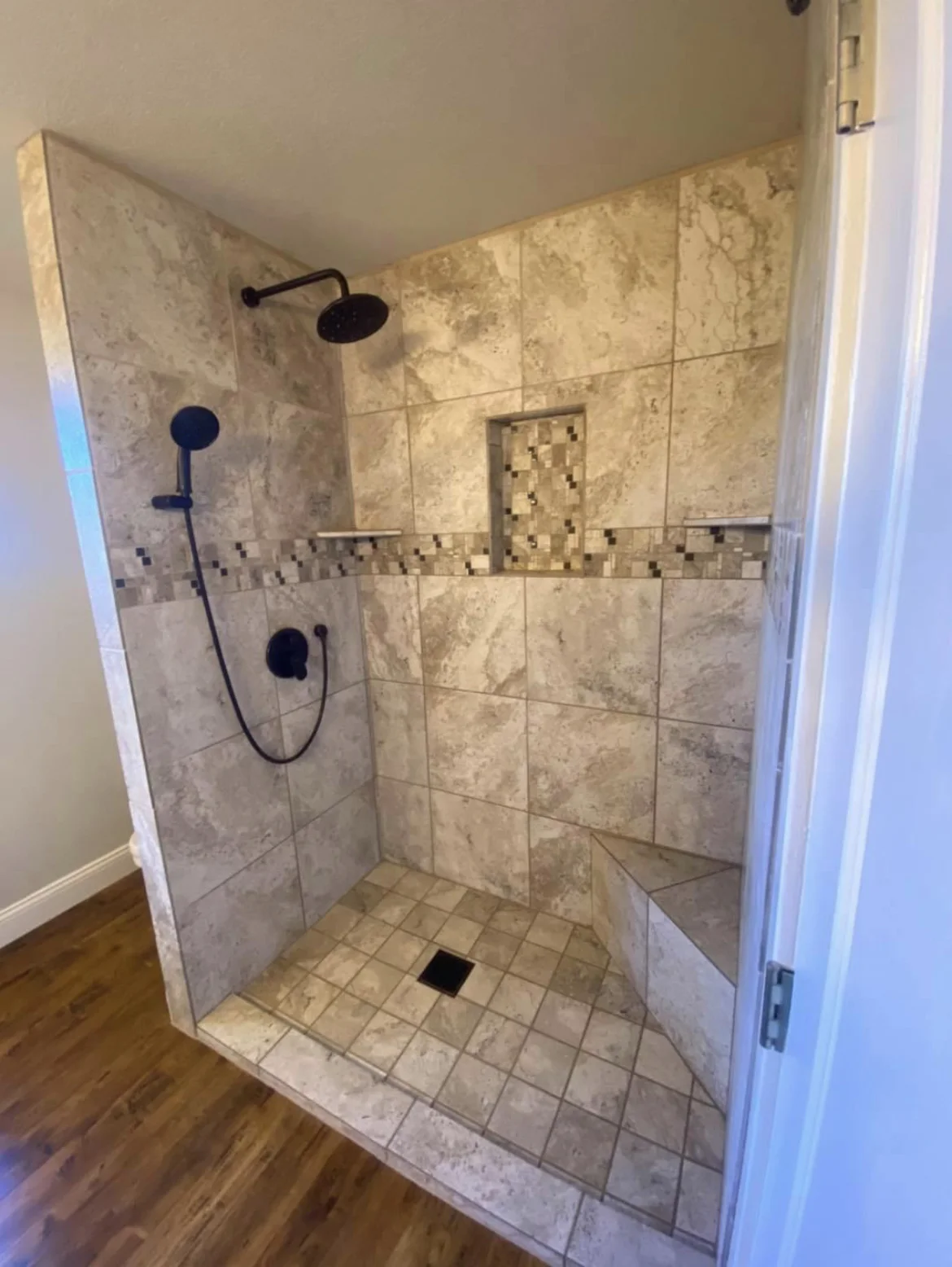 Completed tiled shower with mosaic accent, wall niche and black fixtures